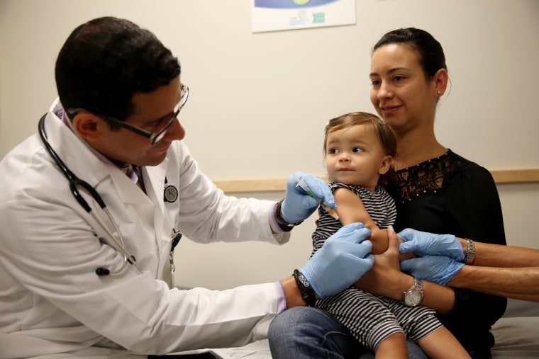Image: Daniela Chavarriaga holds her daughter as a pediatrician administers a measles vaccination