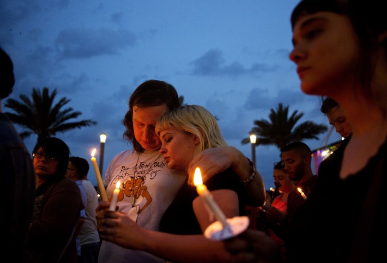 Image: Lucinda Rex, right, and Clarity Thorne embrace during a candlelight vigil downtown for the victims of a mass shooting at the Pulse nightclub