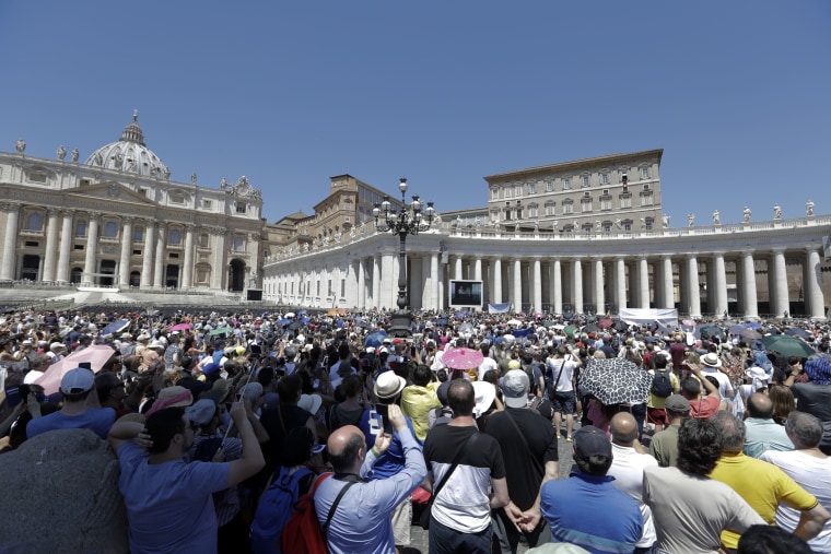 Image: People watch Pope Francis as he recites the Angelus noon prayer from the window of his studio overlooking St. Peter's Square
