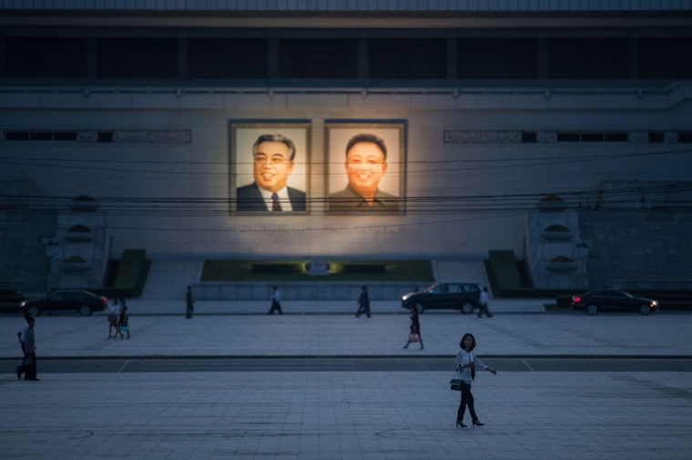 Image: Pedestrians make their way past the portraits of late North Korean leaders