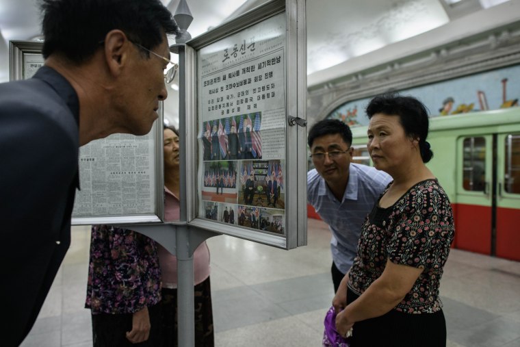 Image: Commuters read the latest edition of the Rodong Sinmun newspaper in Pyongyang