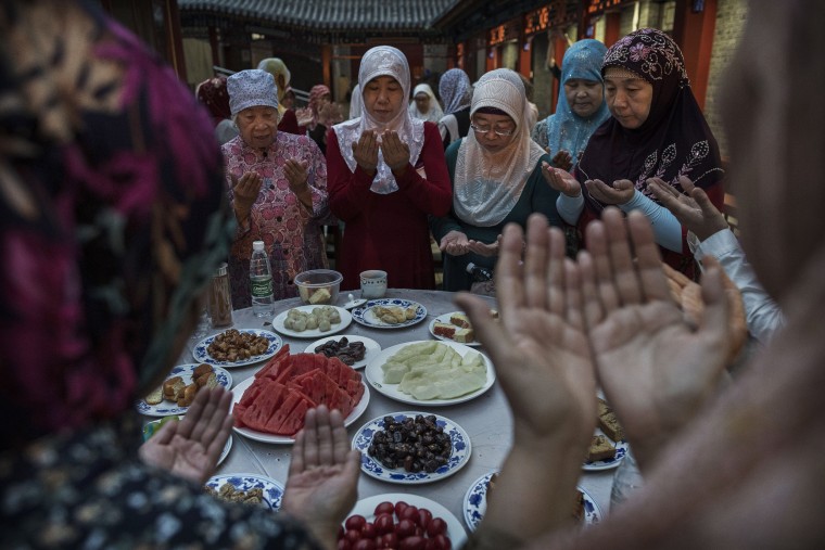 Image: Women from the Hui Muslim community pray over food before breaking their fast