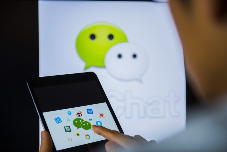 Image: Young man holds a smart device while using WeChat app