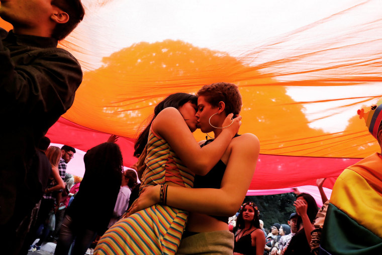 Image: Revellers kiss under a rainbow flag during the Gay Pride parade along Paulista Avenue in Sao Paulo