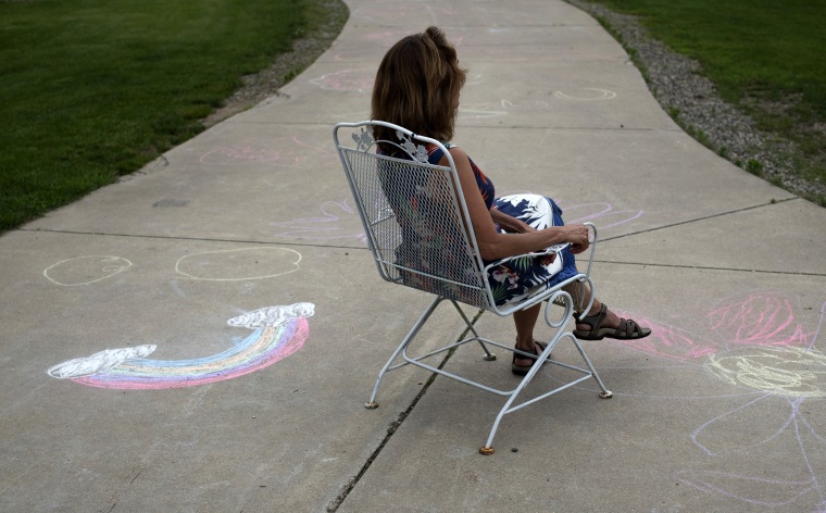Image: Christine sits surrounded by chalk drawings from the unaccompanied migrant children she is currently fostering