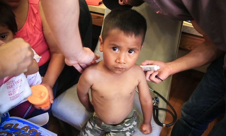 Image: A volunteer pediatrician applies cream to scratches on 3-year-old Juan, a child migrant from rural Guatemala, in El Paso, Texas.