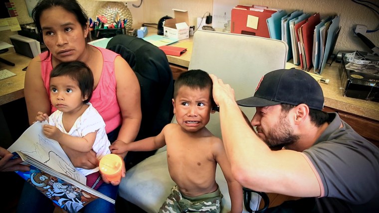 Image: Juan, 3, cries as a volunteer pediatrician examines him.