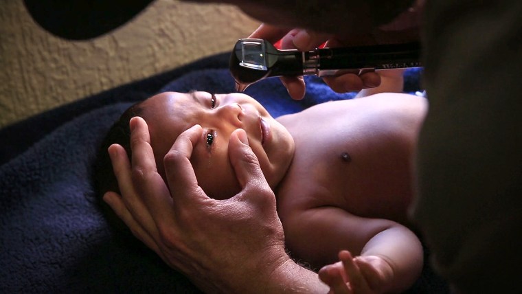Image: Six-month-old Alan Ivan is examined by a volunteer pediatrician.