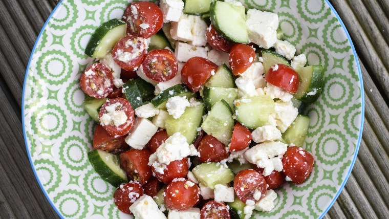 Greek Salad with tomato, cucumber and Feta cheese on a white and green plate.
