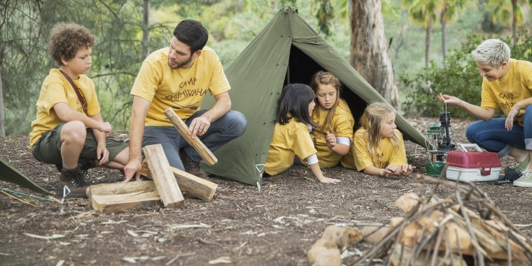 Camp counsellors and children camping in forest