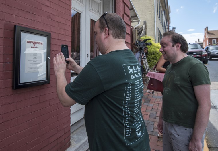 A passerby takes a photo of the menu outside of the Red Hen Restaurant on Saturday in Lexington, Virginia.