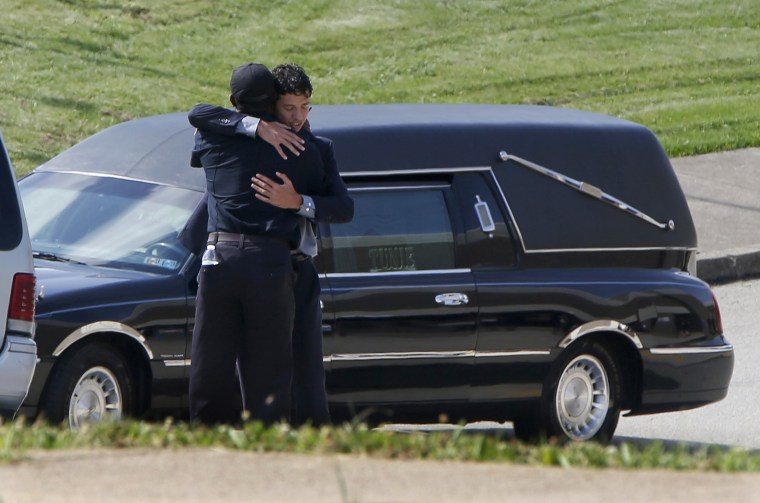 Image: A person attending the funeral for Antwon Rose Jr. embraces a police officer