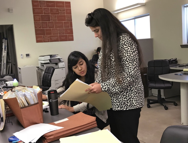 Alexis Bay, standing, and Priscilla Mendoza, law clerks at the Texas Civil Rights Project in Alamo, Texas, check details Monday in the file of a child they have been trying to locate for a father since May 29. 