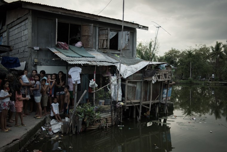 Image: Neighbors watch as the suspect is led away out the cluster of slums in Malolos, in the Philippines