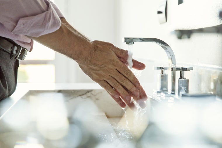 Image: Man washing hands in bathroom sink, cropped