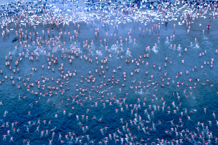 Image: Participants of the Dark Mofo Nude Solstice Swim are seen in the River Derwent at dawn, in Hobart