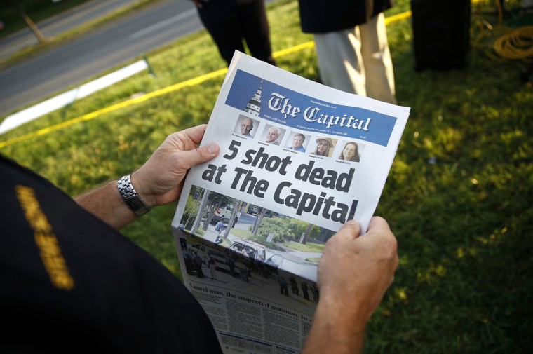 Image: A man holds a copy of The Capital Gazette newspaper