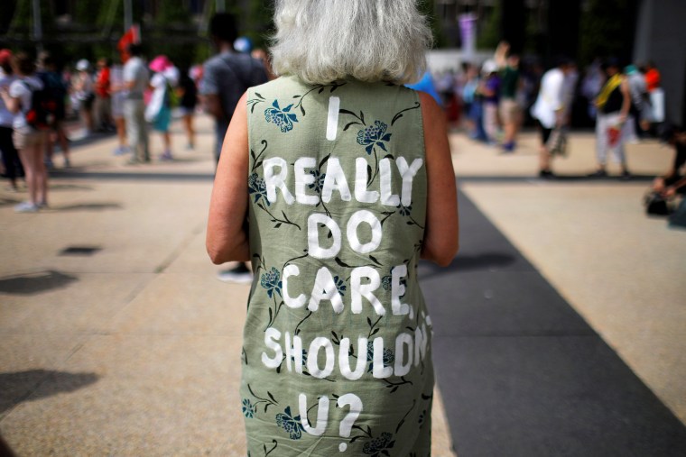 Image: A demonstrator wears a dress reading \"I Really Do Care, Shouldn't U ?\", referencing the coat recently worn by First Lady Melania Trump, during the \"Families Belong Together\" rally in Boston