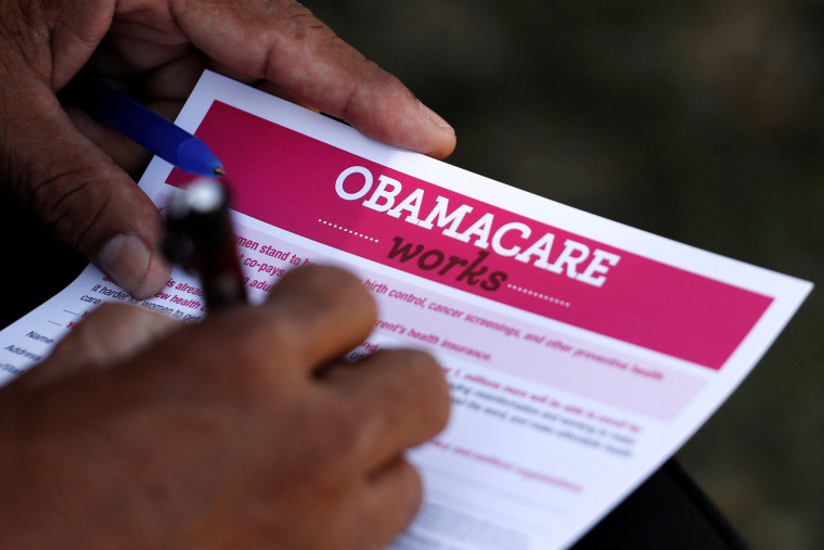 Image: A man fills out an information card during an Affordable Care Act outreach event