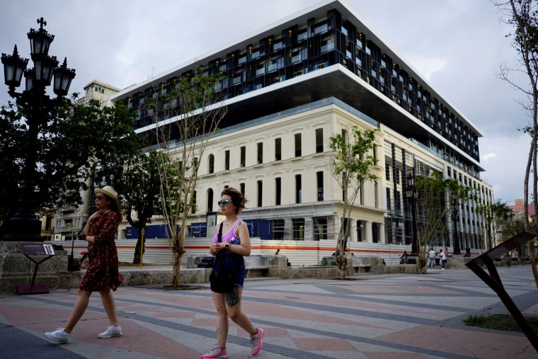 Image: Tourists pass by a hotel under construction at the Paseo del Prado boulevard in Havana