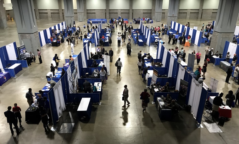 Image: Job seekers mill about employers' booths at a job fair in Washington
