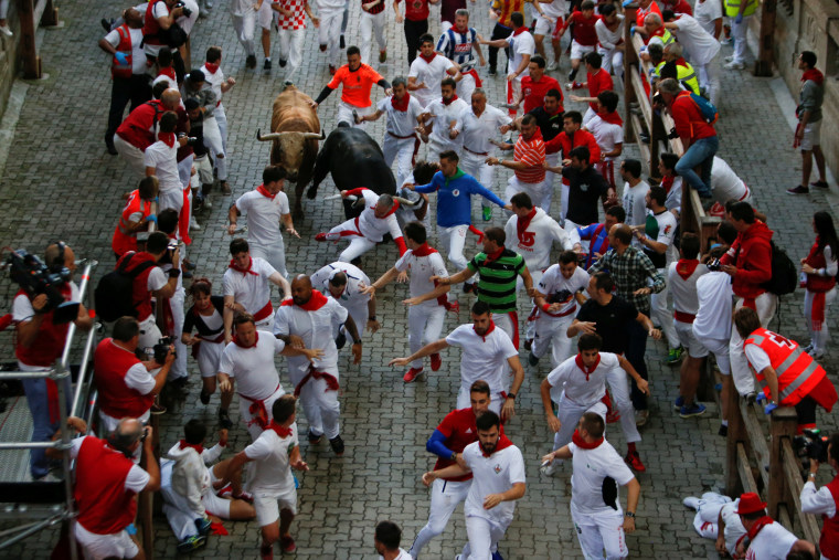 Image: Runners sprint in front of bulls during the fourth running of the bulls of the San Fermin festival in Pamplona