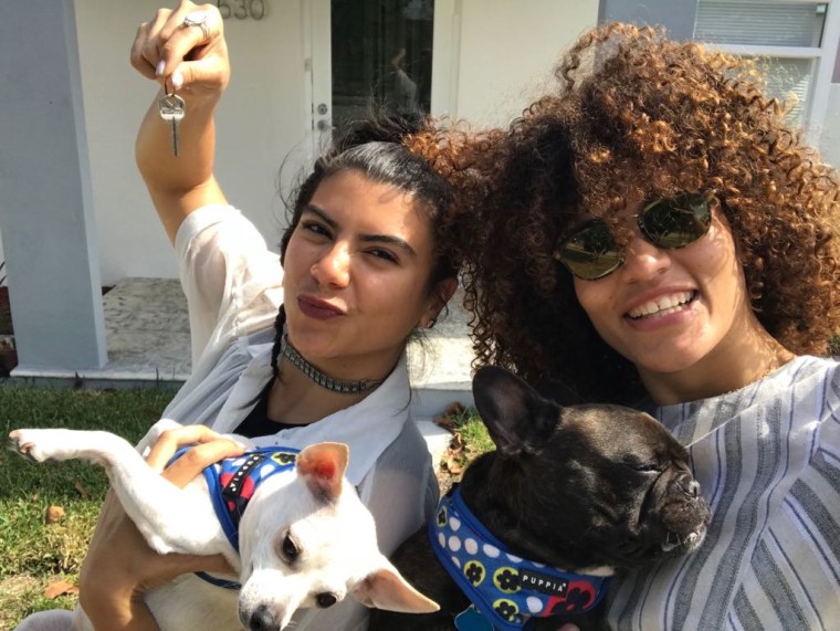 Christian Portilla (left) holds the keys to her new home in Miami, Florida while posing next to her wife, Melani Liriano, and their two dogs.