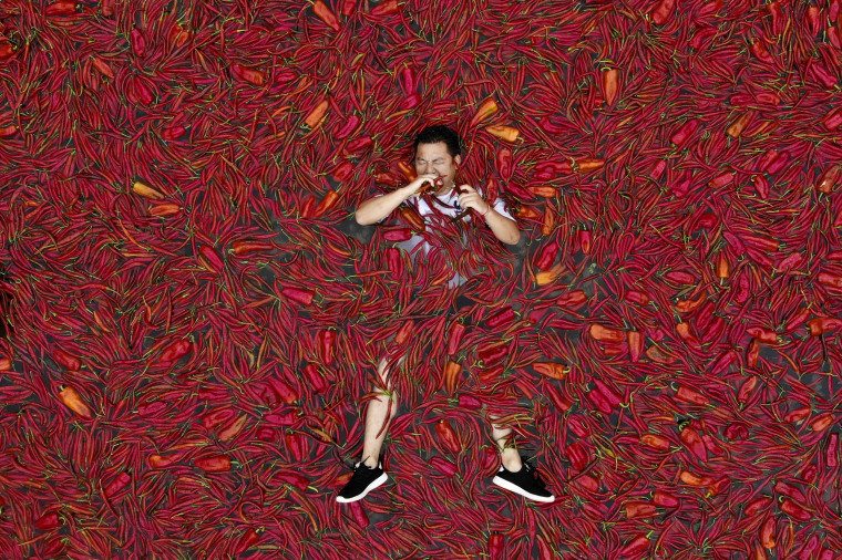 Image: A contestant lays in a pool of red chilies