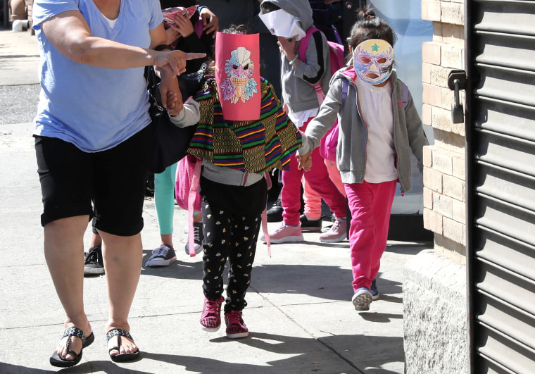 Image: Children, with their faces covered with masks, leave the Cayuga Center, which provides foster care and other services to immigrant children separated from their families, in New York City