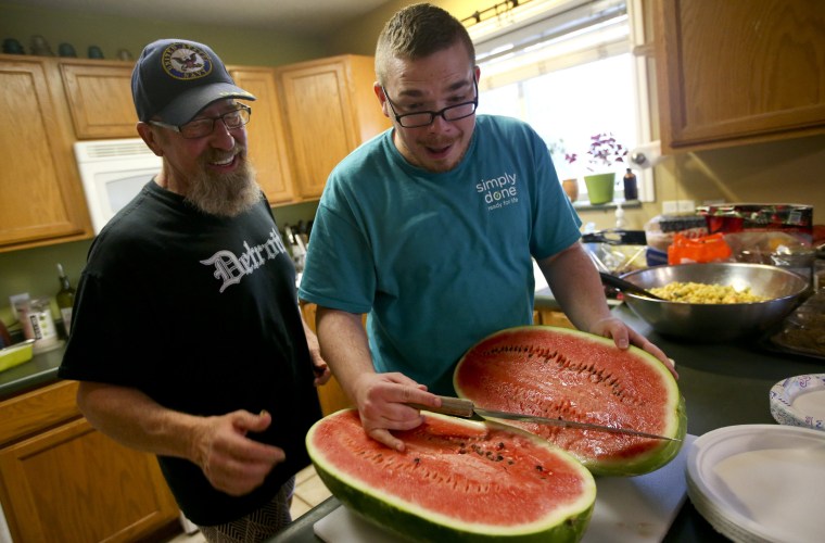 Cameron Raps, right, reacts after cutting open a watermelon beside Jeff Pool during a QueerMeals gathering