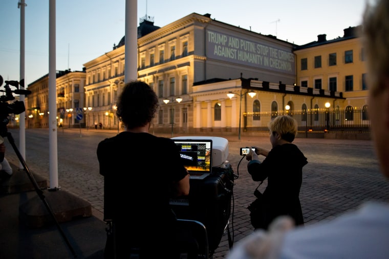 Image: A sign that reads, " Trump and Putin: Stop the Crimes Against Humanity in Chechnya" is projected next to the president's castle