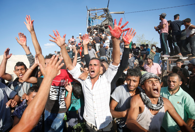 Image: Palestinians react with bloodied hands outside a Hamas outpost that was struck by Israeli bombardment near Khan Yunis in the southern Gaza Strip