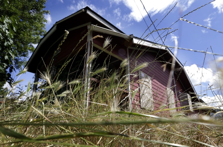 Dense growth surrounds an abandoned, boarded up house in Portland