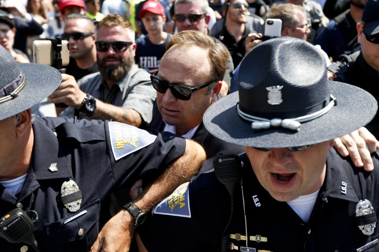 Image: Alex Jones, center, is escorted out of a crowd of protester