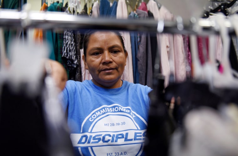Image: Sandra Elizabeth Sanchez, of Honduras, browses through a rack of clothes at Catholic Charities in San Antonio