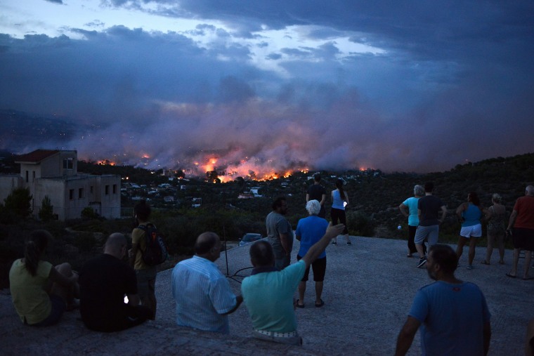 Image: People watch a wildfire in the town of Rafina, Greece
