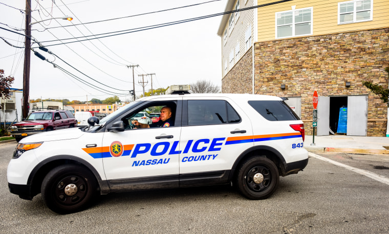 A Nassau County Police officer sits in front of a crime scene