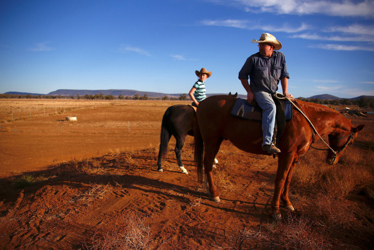 Image: Farmer Scott Cooper and his daughter Charlie ride their horses along a fence in a drought-effected paddock on their property named 'Nundah', located south of the central New South Wales town of Gunnedah