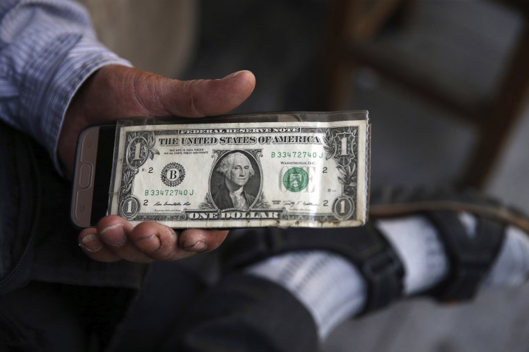 Image: An Iranian street money changer holds a U.S. banknote 