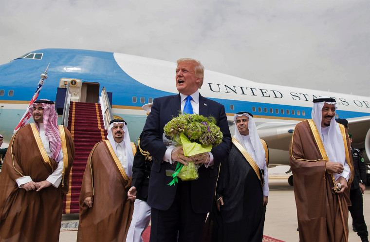 Image: President Donald Trump holds a bouquet of flowers upon being welcomed by Saudi King Salman bin Abdulaziz al-Saud