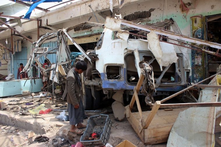 A Yemeni child stands next to a destroyed bus at the site of an air strike in the province of Saada