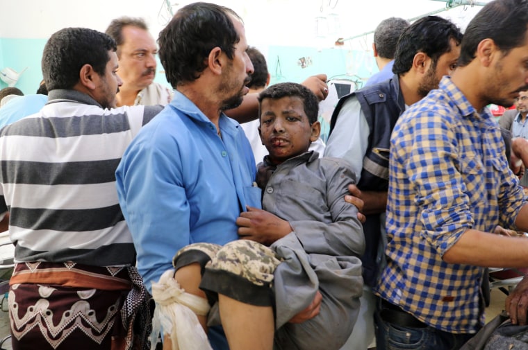 Image: A Yemeni man holds a boy who was injured by an airstrike in Saada