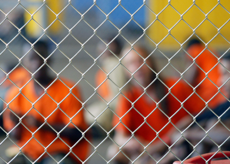 Inmates sit inside holding cell before being transported from New Orleans.