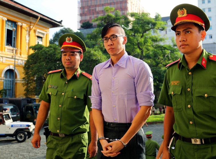 Image: US citizen Will Nguyen is escorted by policemen before his trial at a court in Ho Chi Minh city