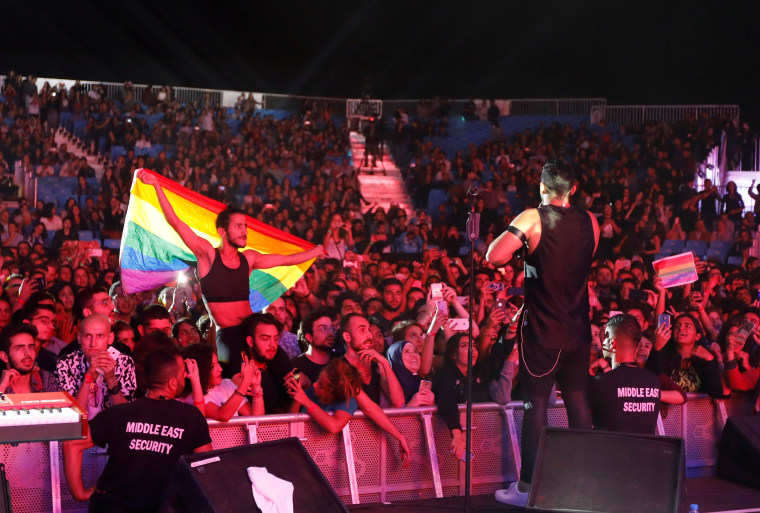 Image: A fan of Lebanese alternative rock band Mashrou' Leila holds a rainbow flag during their concert at the Ehdeniyat International Festival in Ehden town