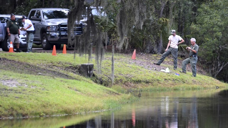 Law enforcement with S.C. Department of Natural Resources take pictures of the site where authorities say Cassandra Cline was dragged into a lagoon by an alligator on Aug. 20, 2018, on Hilton Head Island, South Carolina.