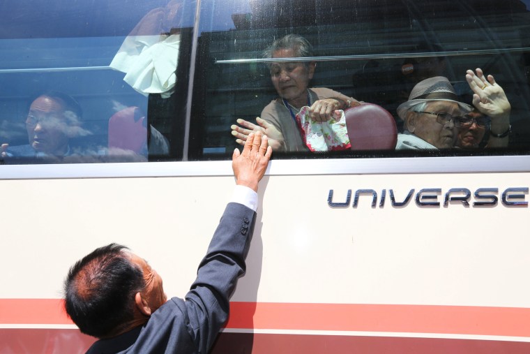 Image: South Korean Lee Keum-seom bids farewell through the bus window to her son Ri Sang Chol