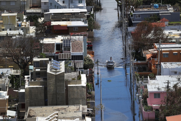 Image: A man stands on a car on a  flooded street in the aftermath of Hurricane Maria in San Juan