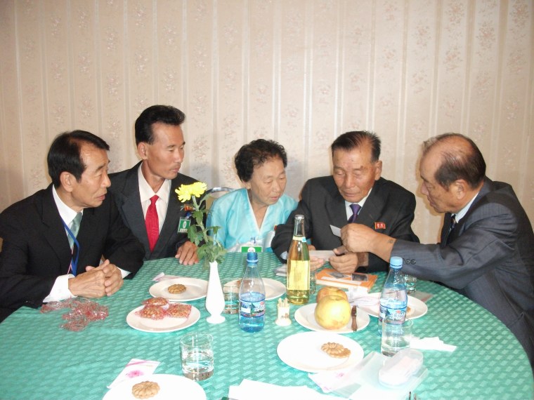 Image: Lee Soo-nam, far right, shows his brother seated next to him photos salvaged after their separation in August 1950