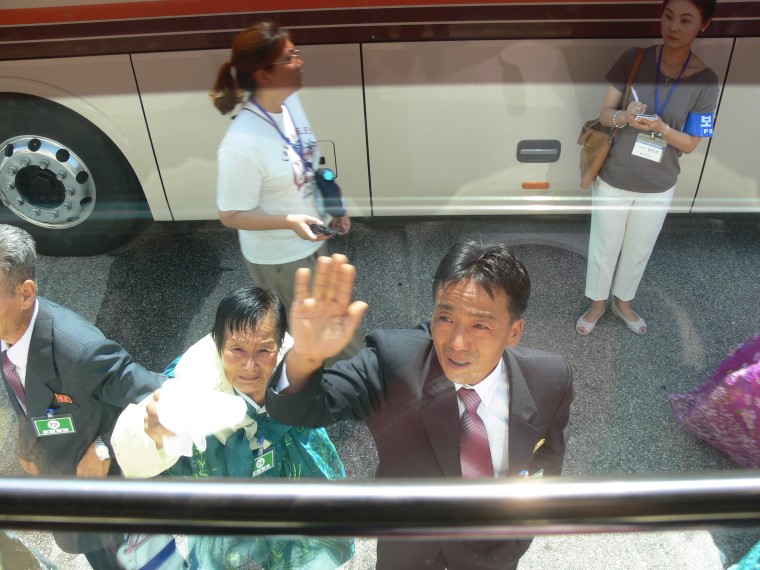 Image: Chung Hak-soon's sister-in-law and nephew wave goodbye to her outside the bus that will take her back to South Korea